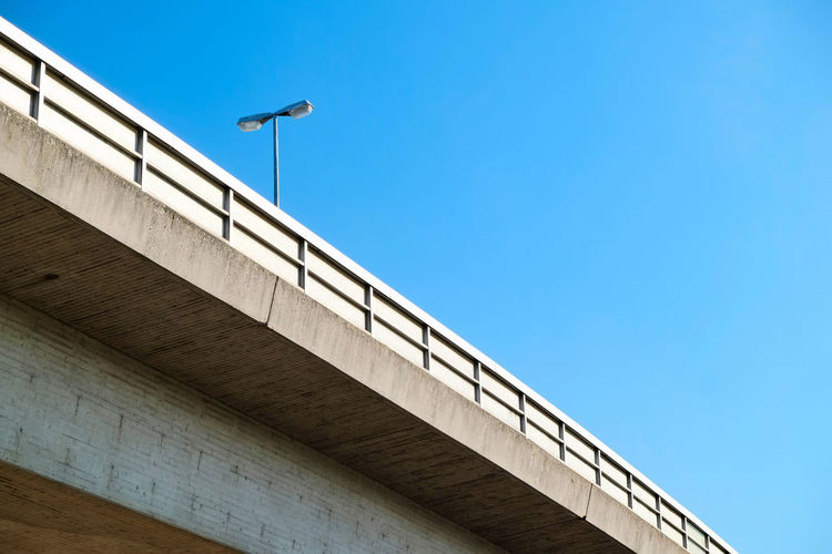 Low angle view of street light on bridge against clear blue sky