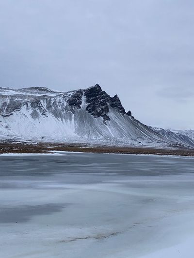 Scenic view of frozen lake by snowcapped mountain against sky