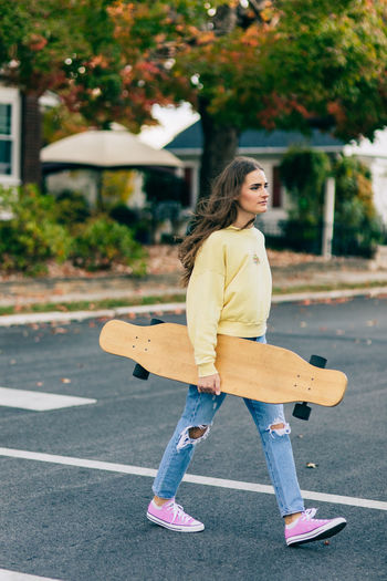 Full length of woman skateboarding on road in city