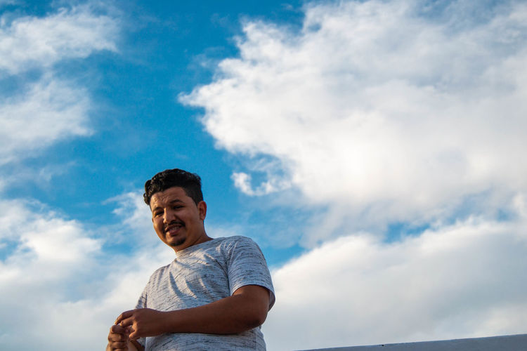 Portrait of smiling man standing against sky