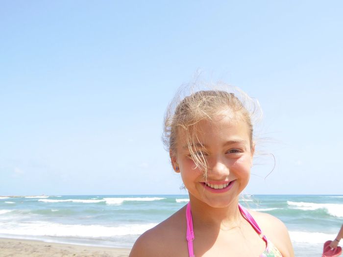 Portrait of smiling girl on beach against sky