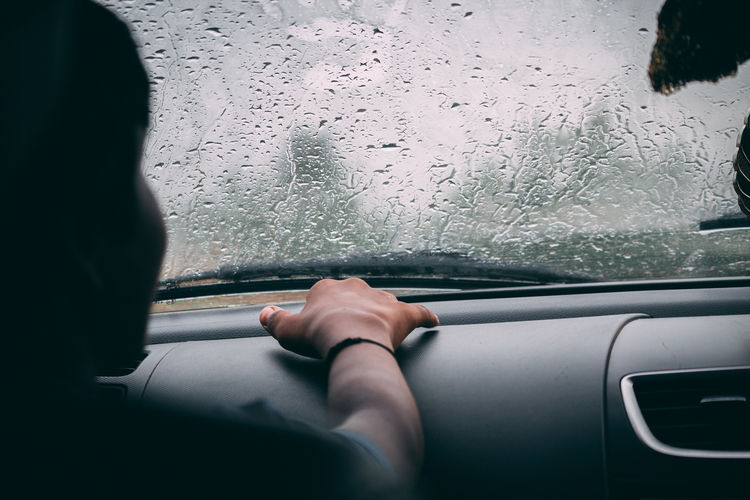 Boy sitting in car during rainy season
