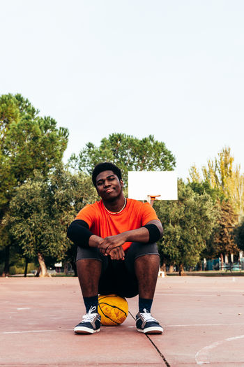 Portrait of young man sitting at basketball court