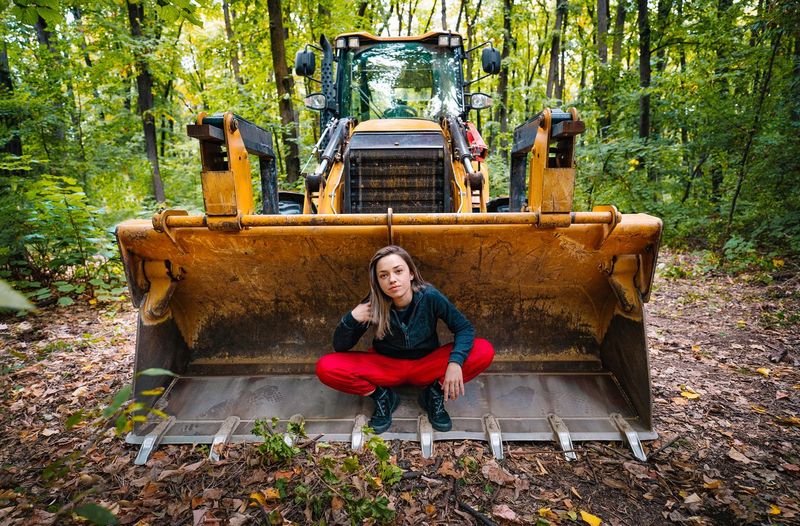 Portrait of woman sitting on excavator in forest