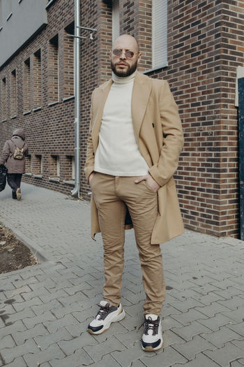 Portrait of young man standing against brick wall
