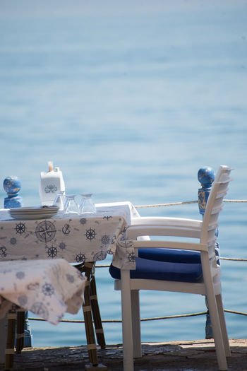 View of chair and table on pier against sea