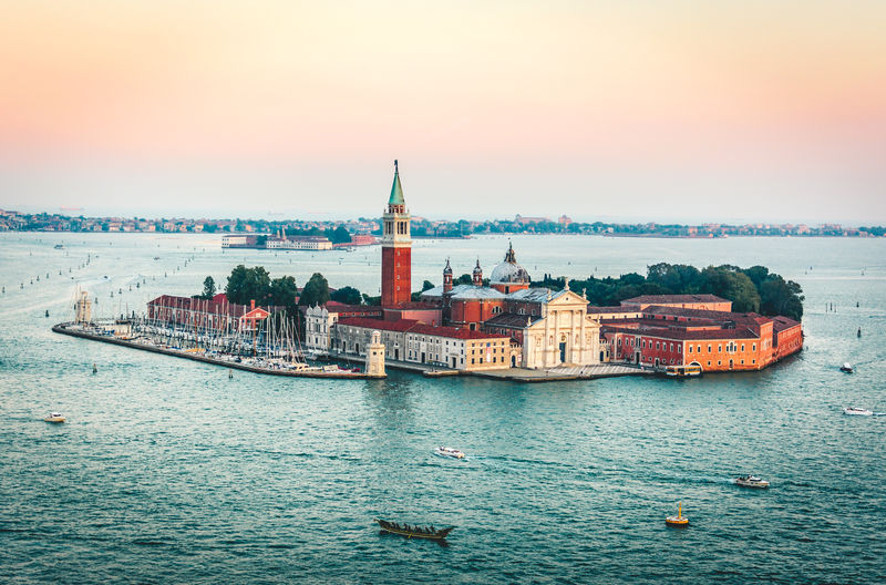 View of buildings in sea against sky during sunset