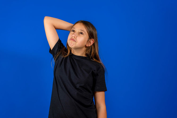 Low angle view of girl standing against blue background