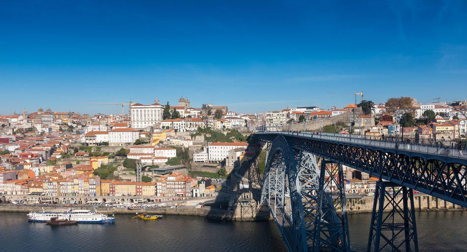Bridge over river amidst buildings in city against sky