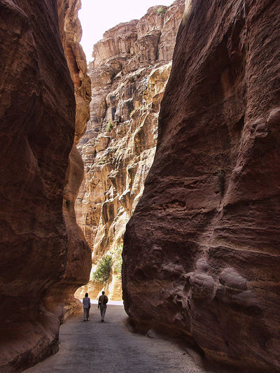 Rear view of people walking amidst rock formations