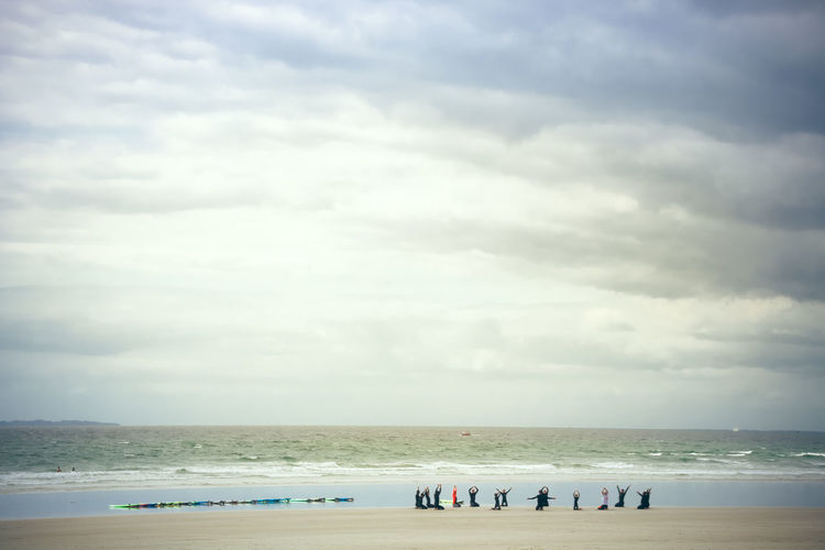People at beach against cloudy sky