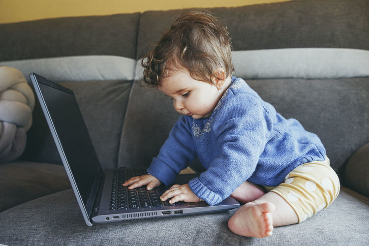 Boy using mobile phone while sitting on sofa at home