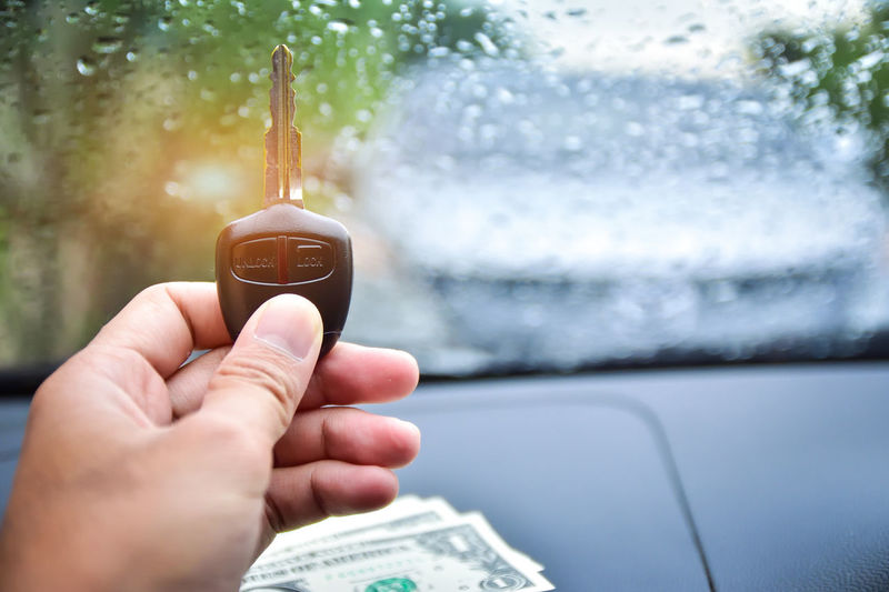 Cropped hand of man holding key in car during rainfall