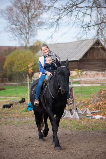 Woman sitting with baby boy on horse at field