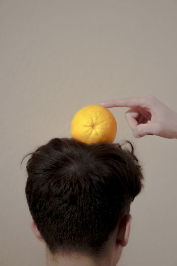 Close-up of man holding orange against white background