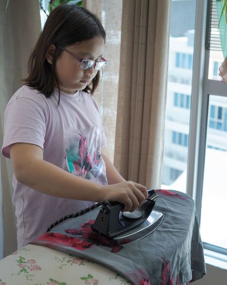 Girl ironing clothes at home