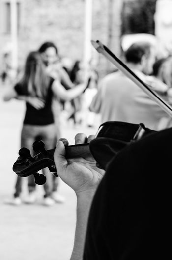 Close-up of man playing violin with couple dancing in background