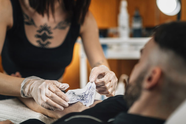 Tattooist removing stencil from a clients arm