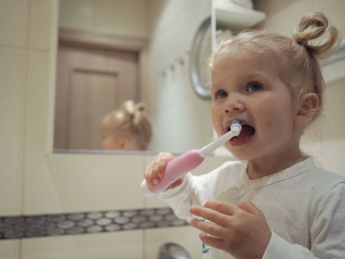 Close-up of girl brushing teeth at bathroom