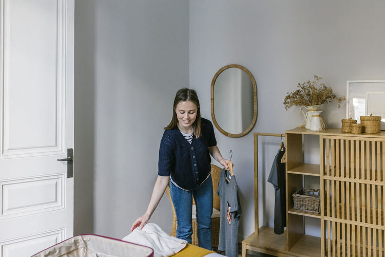 Smiling woman arranging clothes in vacation apartment