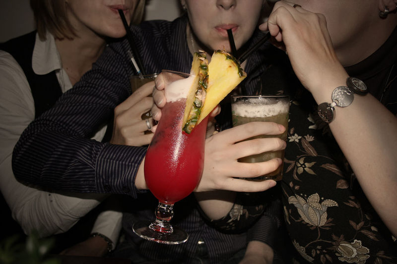 Midsection of friends drinking cocktails at nightclub