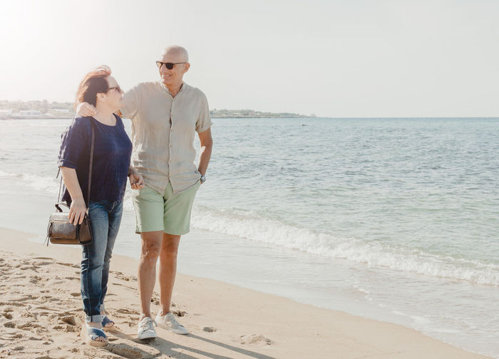 Full length of senior couple standing on beach