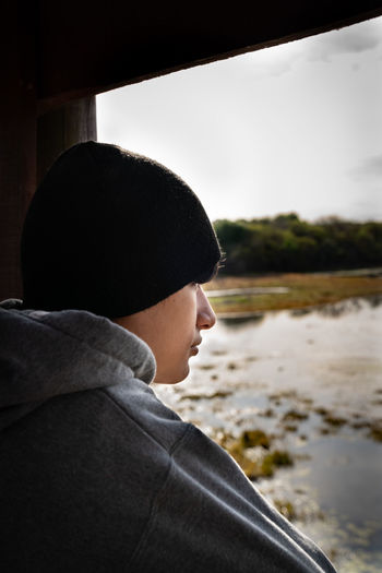 Young man looking at the lake at sunset