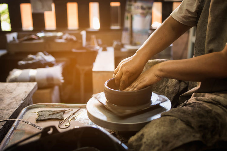 Midsection of potter making pottery at workshop