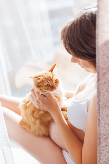 Pregnant woman in white underwear with cute ginger cat. risk of infection toxoplasmosis.