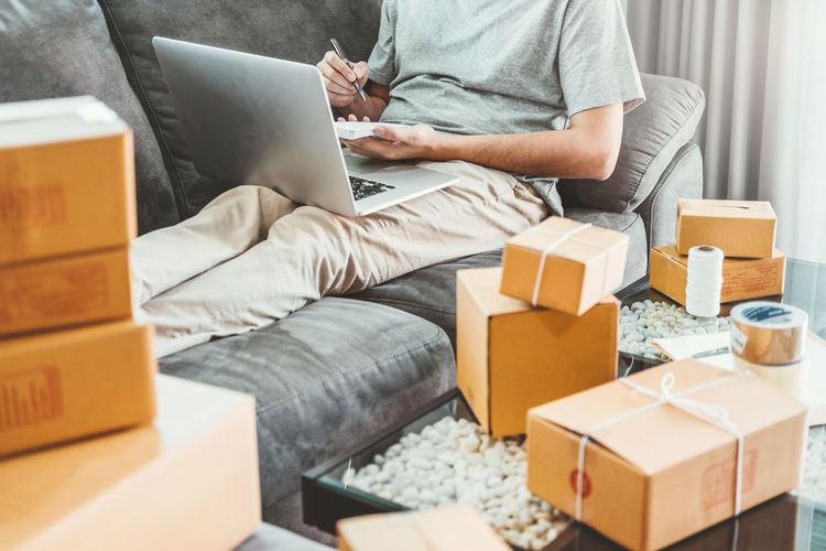 Midsection of man using laptop while delivering boxes