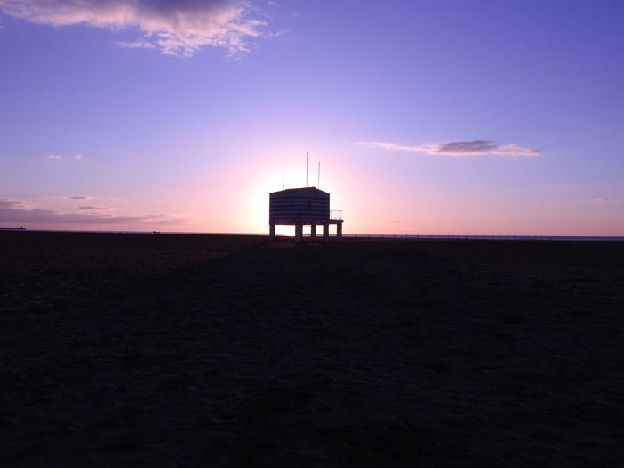 Lifeguard hut at beach against sky during sunset