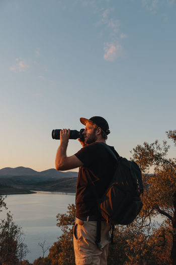 Man photographing against sky at sunset