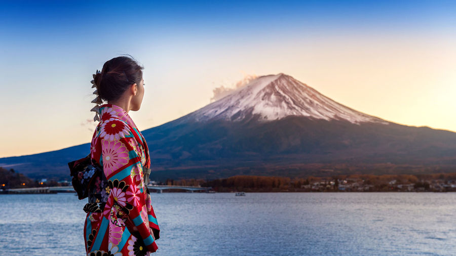Side view of woman in kimono standing against mt fuji during winter