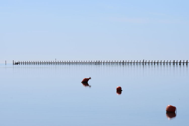 Reflection of man in water against clear sky