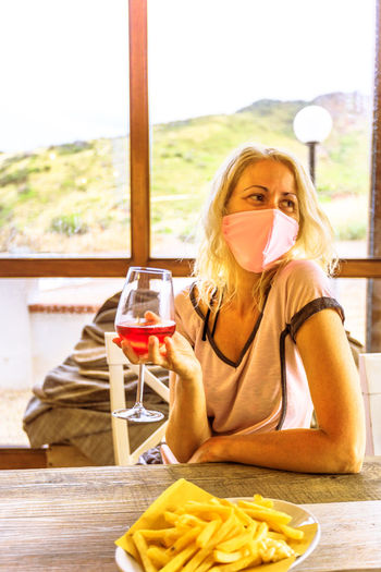 Portrait of young woman drinking glasses on table