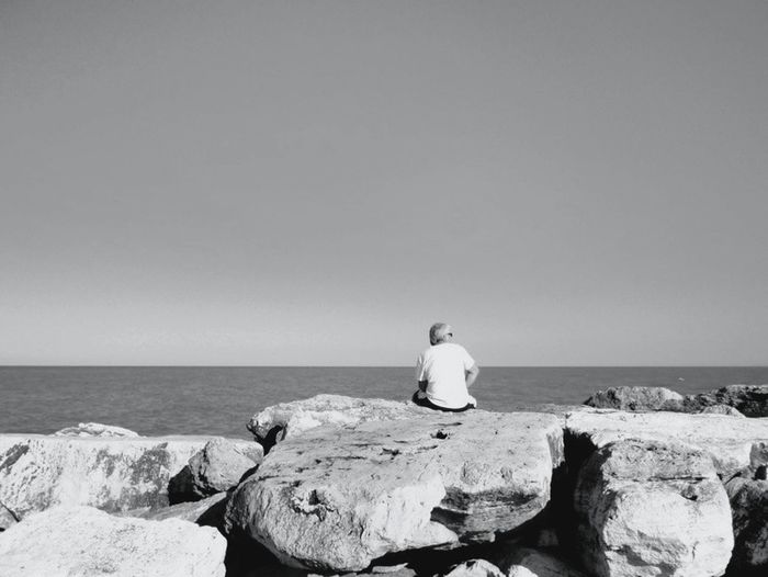 Man sitting on rock at seaside