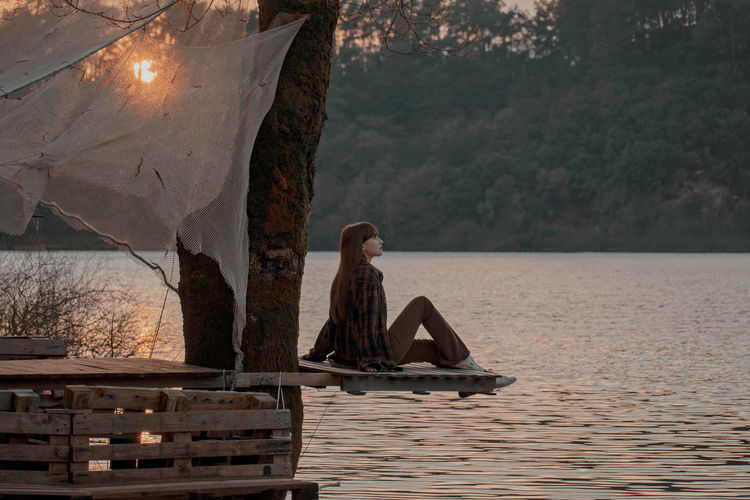 Rear view of woman standing by lake