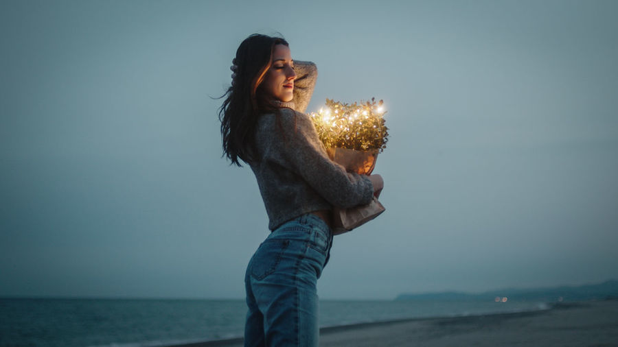 Happy young girl enjoys life on the beach with colorful lights on bag