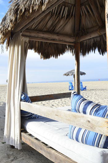 Tropical outdoor beach bed   thatched roof, curtains,, pillows for  glamping relaxation seashore