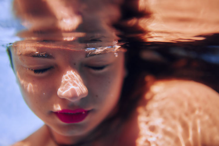 Close-up underwater, of young woman.  the face and skin of a girl, swims in the pool, bubbles. water