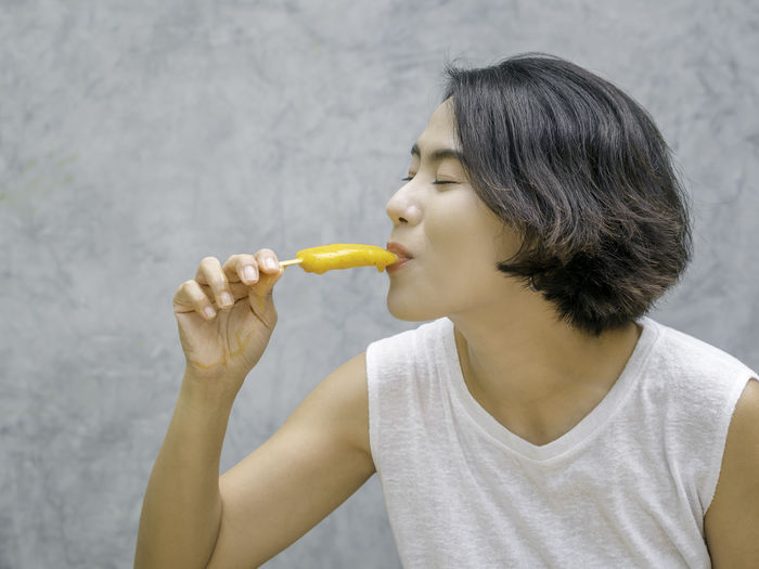 Midsection of woman eating food against wall