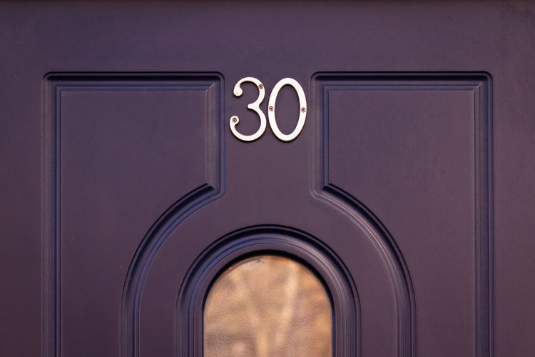 House number 30 on a wooden front door in london with glass window