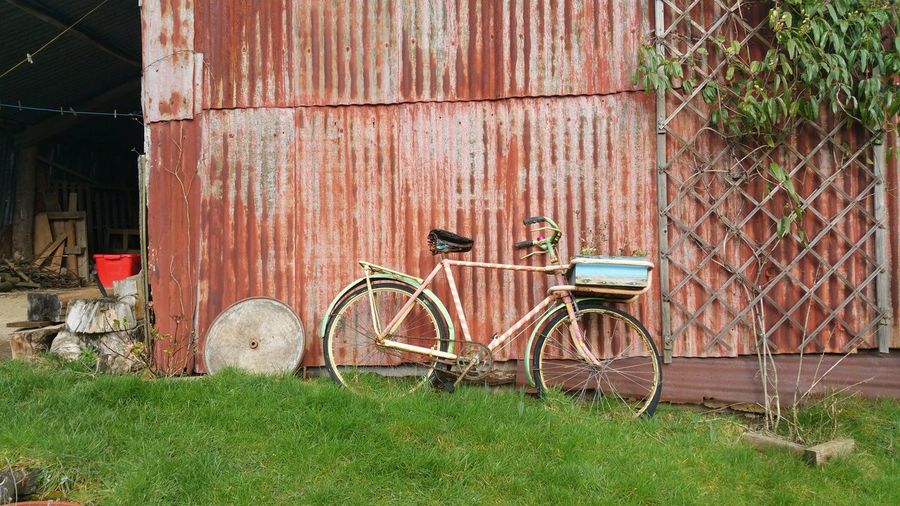 Bicycle parked on field against barn