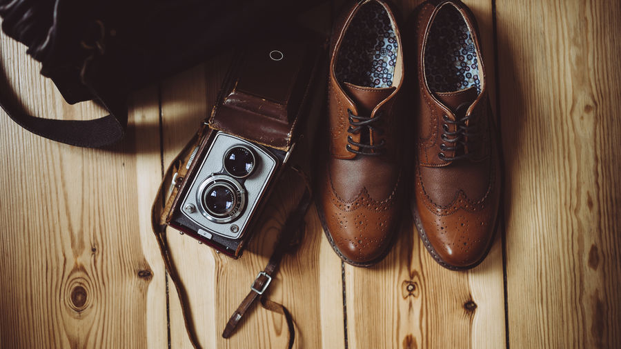 Directly above shot of shoes and camera on floorboard