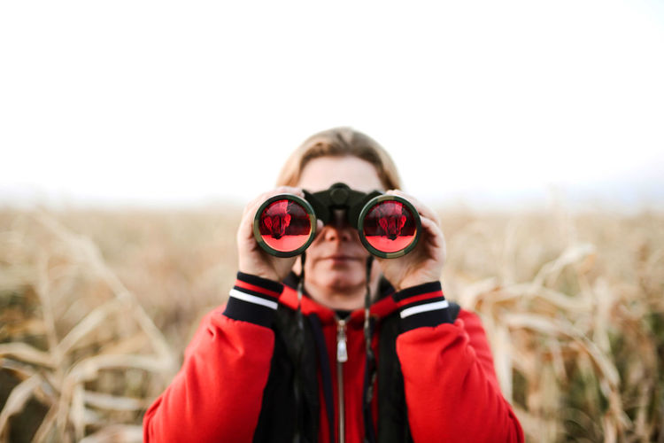 Woman holding binoculars at farm