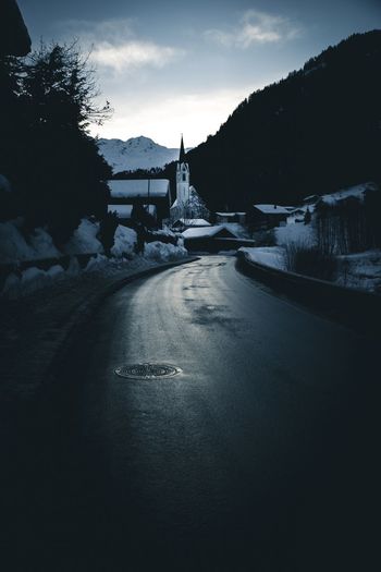 Road by snowcapped mountain against sky during winter