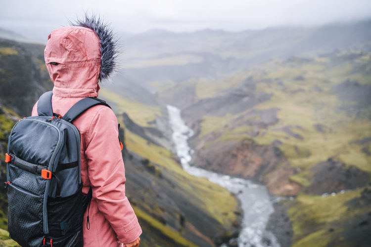Woman with backpack enjoying icelandic river fossa close to haifoss waterfall in iceland