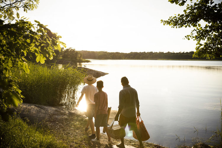 Family with picnic supplies walking at lakeshore during summer vacation