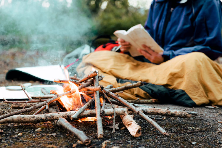 Young female backpacker making notes at campfire