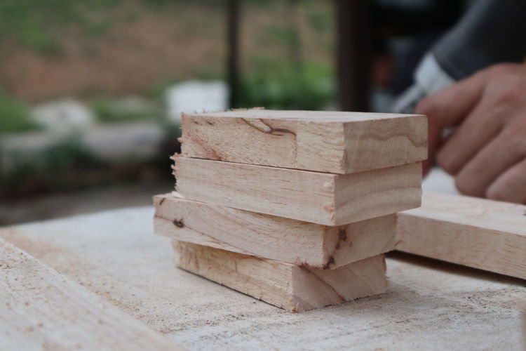Midsection of man sitting with stacked wooden blocks on table